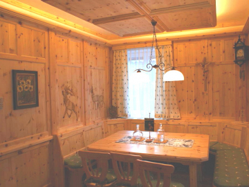 Rustikale Zirbenstube mit Wandverkleidung, Holzdecke mit indirekter Beleuchtung und aufwendige Schnitzerei an den Wänden
