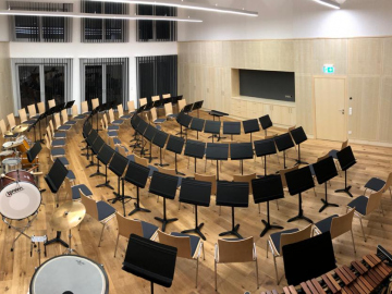 Orchesterproberaum mit Wand und Decken Akustikpaneelen aus Holz. Integrierte Stauraummöbel Ahorn furniert mit gelochten Akustik-Fronten.